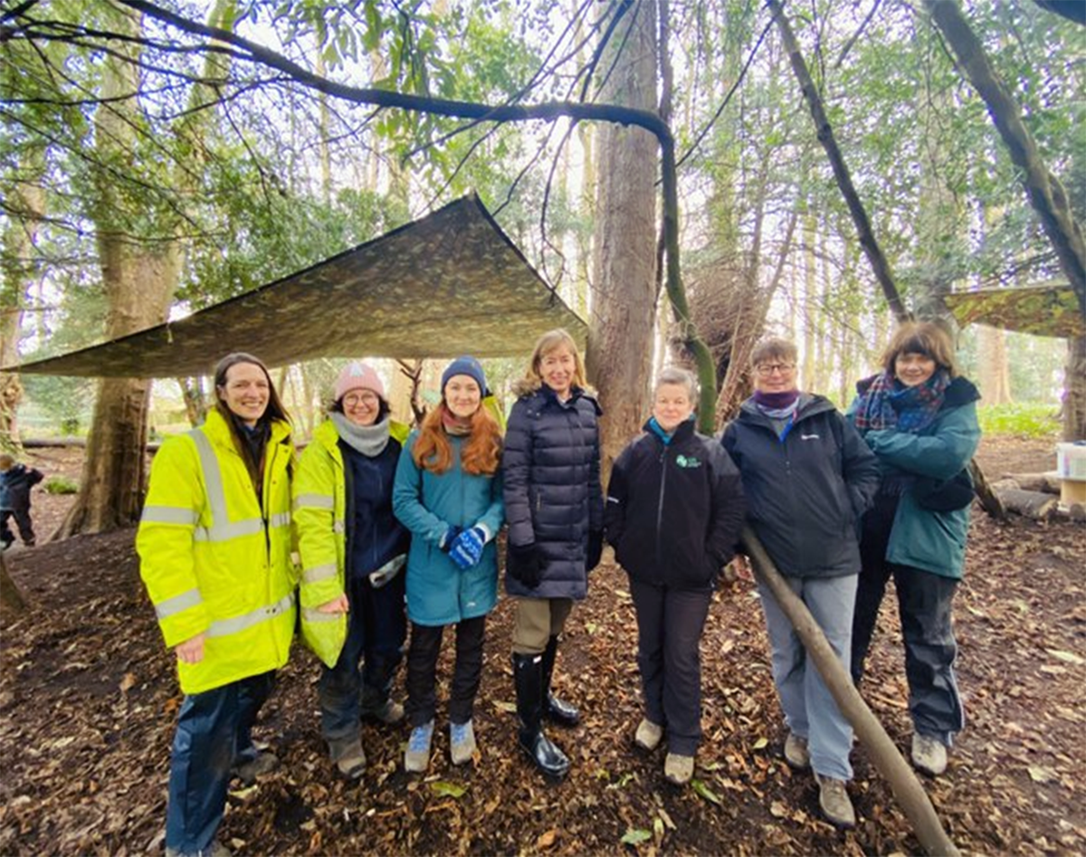 A local community group smiling at the camera in a local woodland.